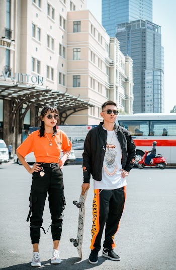 Photo of Woman Standing Near Man Holding a Skateboard