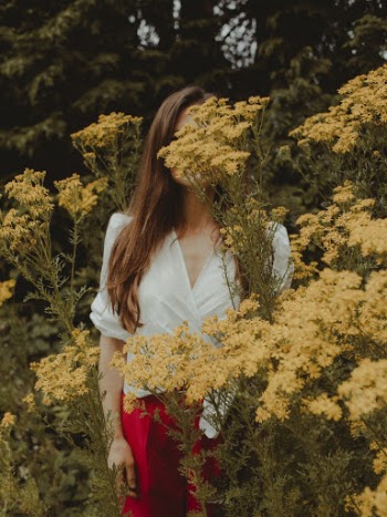Photo of Woman Standing Near Yellow Petaled Flowers