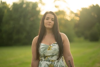 Photo of Woman Standing on Green Grass Field Wearing Strapless Floral Dress