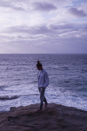 Photo of Woman Standing On Rock Near Ocean