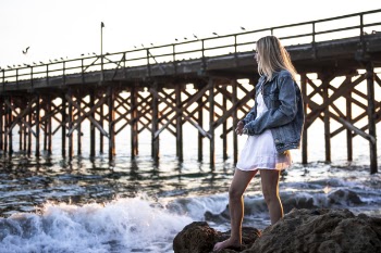 Photo of Woman Standing On Rock Near Sea
