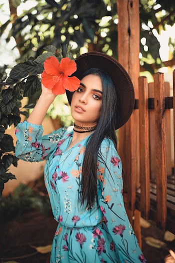 Photo of Woman Standing While Holding Orange Petaled Flower