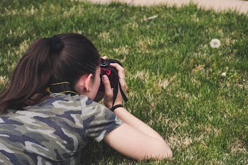 Photo of Woman Taking Photo of Flower on Grass