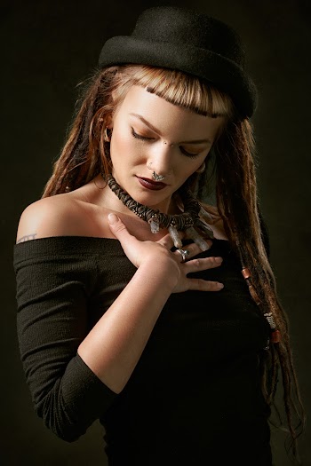Photo of Woman Wearing Black Hat and Off-shoulder 3/4-sleeved Dress Touching Her Chest Posing