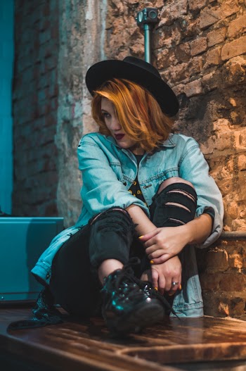Photo of Woman Wearing Blue Denim Jacket Sitting Beside Wall