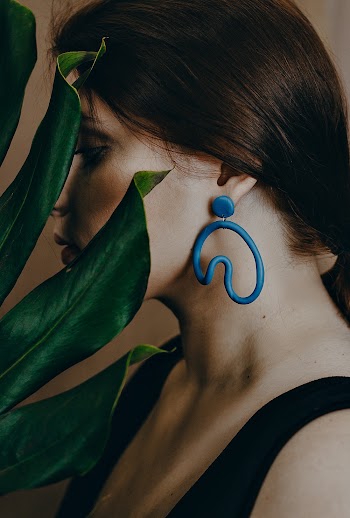 Photo of Woman Wearing Blue Earring Near Green Leaves