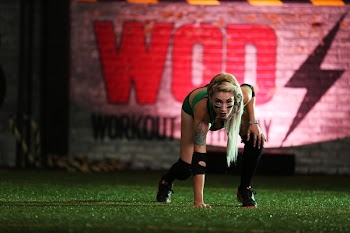 Photo of Woman Wearing Green Top and Black Shorts Touching Grass