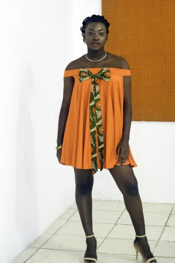 Photo of Woman Wearing Orange Off-shoulder Dress Standing Near White Wall