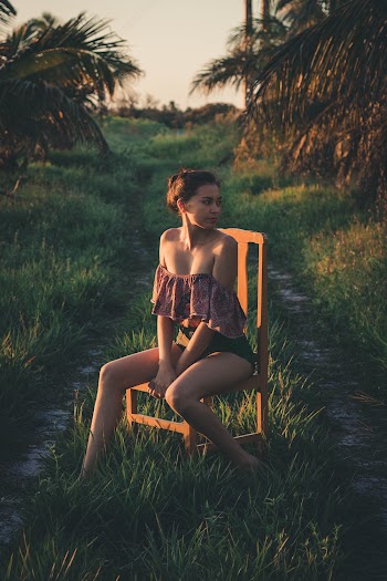 Photo of Woman Wearing Tube Blouse While Sitting on Wooden Chair