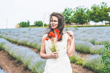 Photo of Woman Wearing White Dress Holding Flower