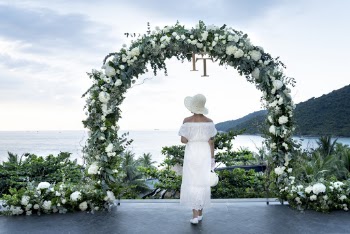 Photo of Woman Wearing White Dress Near Flower Arbor