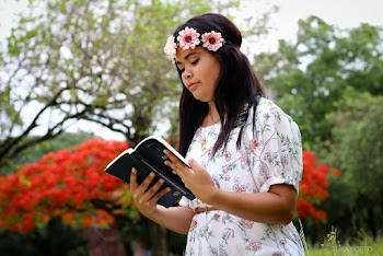 Photo of Woman Wearing White Floral Dress While Holding Book