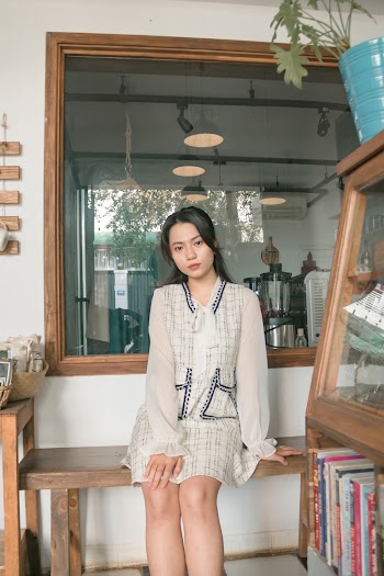Photo of Woman Wearing White Long-sleeved Dress Sitting on Wooden Bench