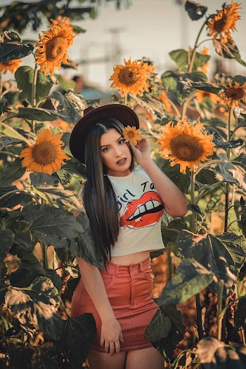 Photo of Woman Wearing White Shirt While Standing Near Sunflowers