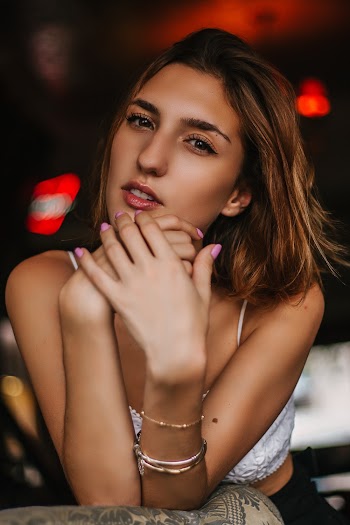 Photo of Woman Wearing White Spaghetti-strap Crop Top Leaning on Her Elbows