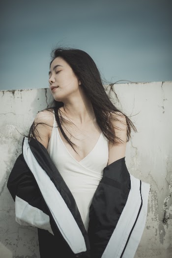 Photo of Woman Wearing White Spaghetti Strap Shirt Leaning on Wall