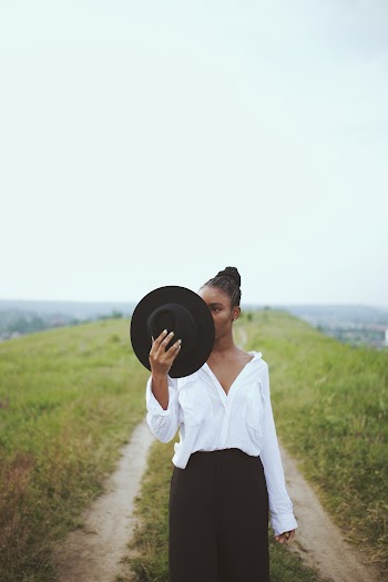 Photo of Woman Wearing White Top Holding Fedora