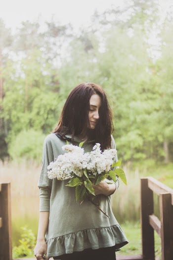 Photo of Woman With Her Eyes Closed Carrying White Petaled Flowers