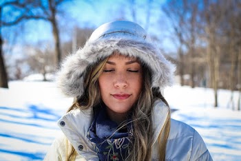 Photo of Woman With Her Eyes Closed in Fur Hooded Coat During Winter