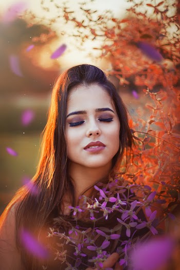 Photo of Woman With Her Eyes Closed Standing Beside Flowers