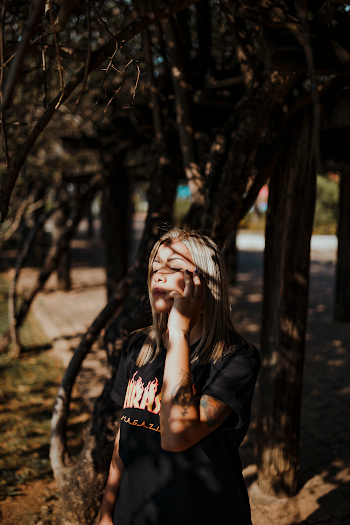 Photo of Woman With Her Eyes Closed Standing Beside Trees Sun Basking