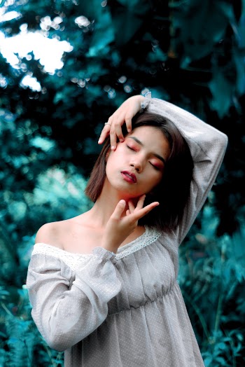 Photo of Woman With Her Eyes Closed Standing In Front of Green-leafed Plants
