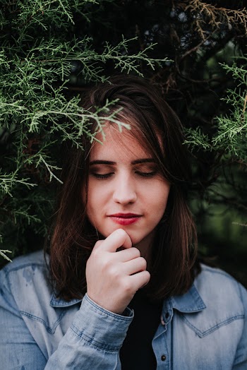 Photo of Woman with Her Eyes Closed Standing Under a Spruce Tree