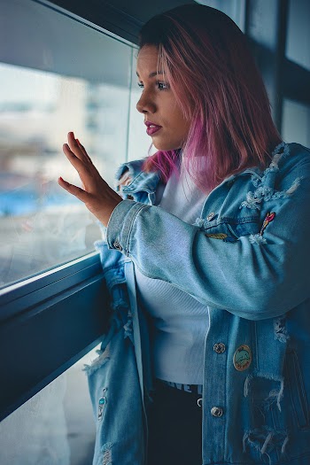 Photo of Woman With Pink Hair Standing by a Window