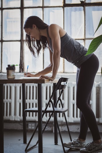 Photo of Woman Writing on Wooden Table