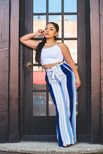 Photo of Women in White Crop Top and Blue and White Palazzo Pants Posing In Front of Wooden Door