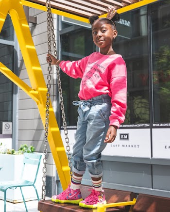 Photo of Young Girl in Pink Sweatshirt and Blue Jeans Standing on Swinging Bench Posing