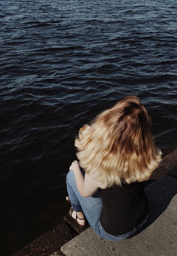 Photograph of a woman sitting near a body of water