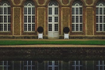 photograph of brown concrete structure with glass windows near body of water