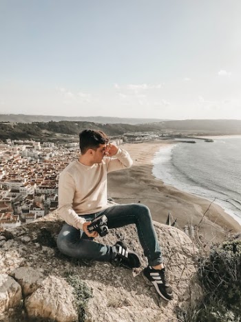 Photographer Holding DSLR Camera Sitting on a Huge Rock
