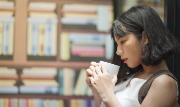Photography of A Woman Holding White Coffee Mug