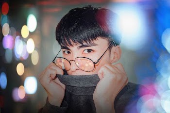 photography of man in gray sweater covering his mouth