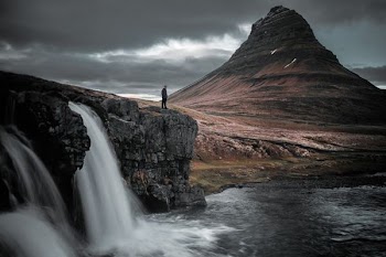 photography of man standing of top of mountain