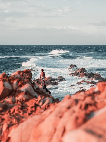 Photography of Man Standing on Rock Formation Beside Seashore