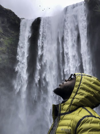 Photography of Man Wearing Bubble Hoodie Jacket Near Waterfalls