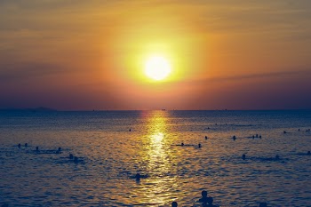 Photography of People Swimming In The Sea During Sunset