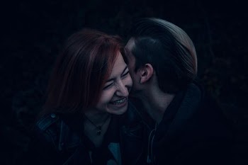 photography of two person whispering against black background