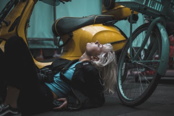 Photography of Woman Laying on Ground Near Scooter