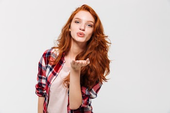 Picture of pleased ginger woman in shirt sends air kiss Free Photo