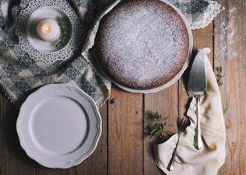 pie on white ceramic plate beside white tealight candle and cake server