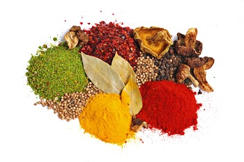 Piles of spices: parsley, red paprika, whole black pepper, white coriander, curcuma, laurel leaves and dry porcini mushrooms.