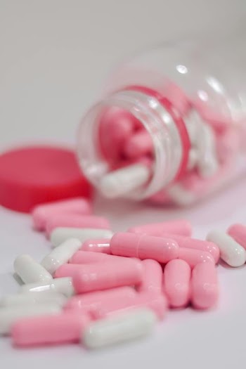 Pink and White Capsules in Open Bottle