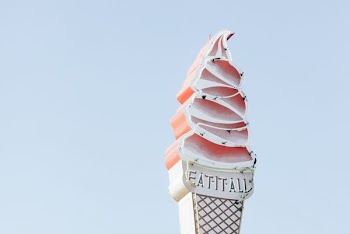 pink and white Fat It All neon signage during daytime