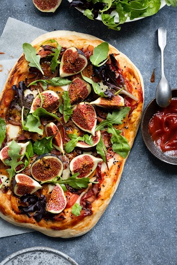 Pizza with tomatoes ham mozzarella and figs flat lay