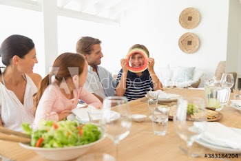 Playful boy with watermelon ring at table with family