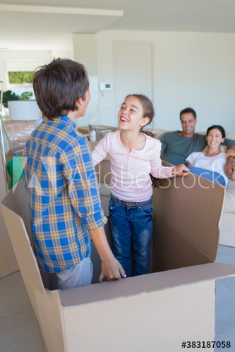 Playful brother and sister inside moving cardboard box